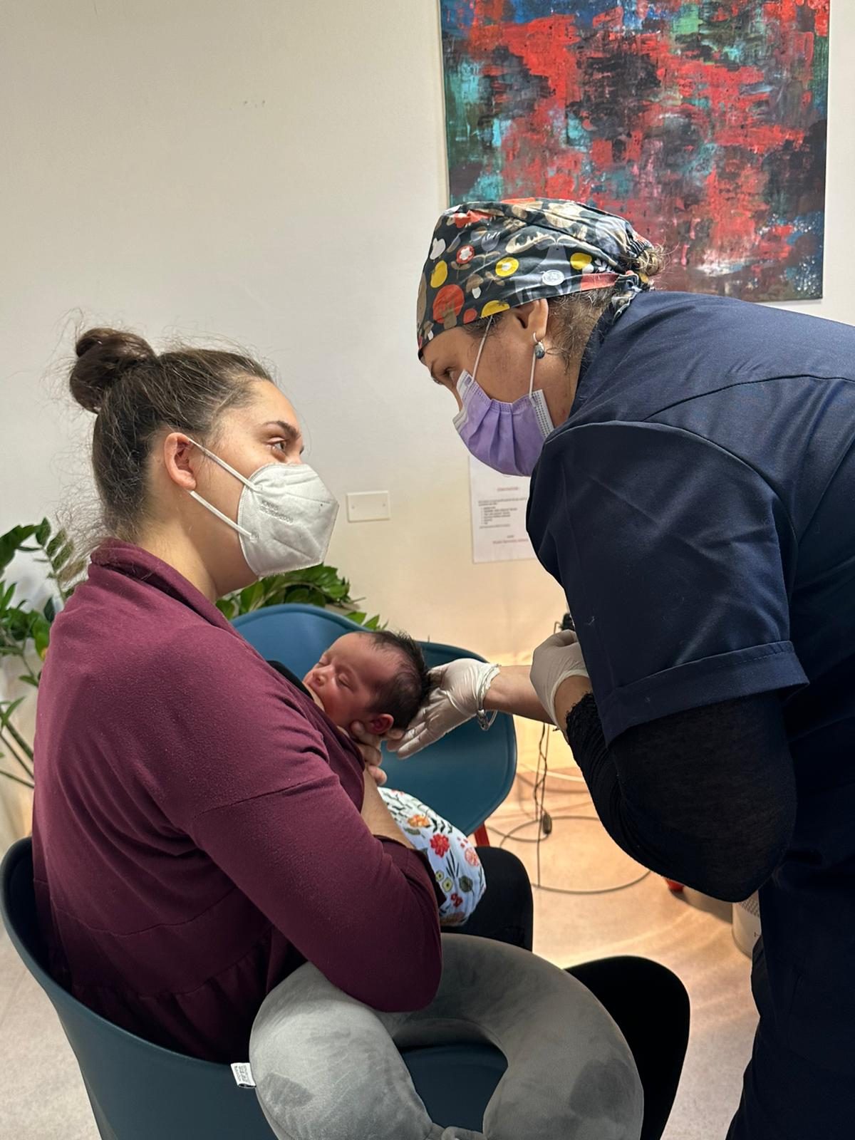 Valutazione del frenulo durante l’allattamento, con la mamma che tiene in braccio il neonato